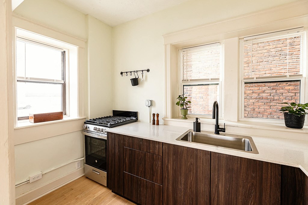 a kitchen with a sink and a stove and two windows