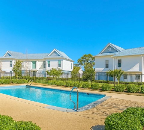 A swimming pool in front of a row of houses.