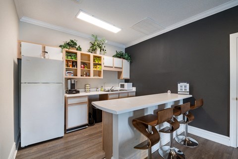 A kitchen with a white counter and bar stools.