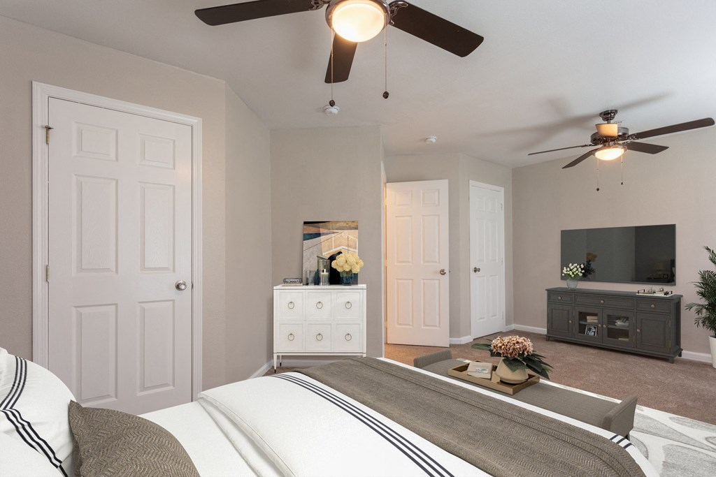 a bedroom with a ceiling fan and tv