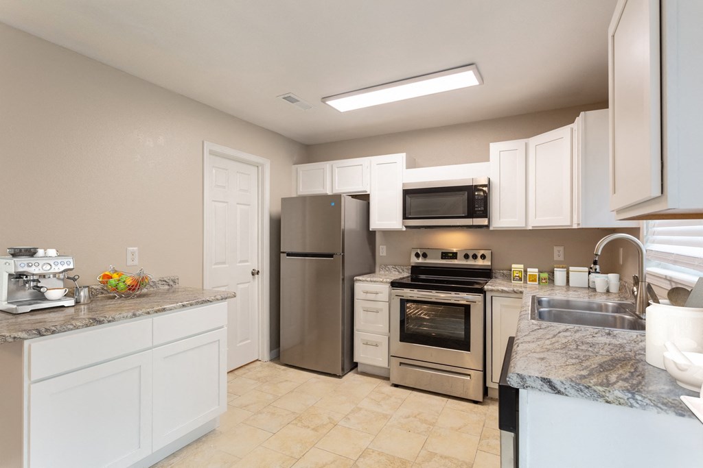 a kitchen with white cabinets and stainless steel appliances
