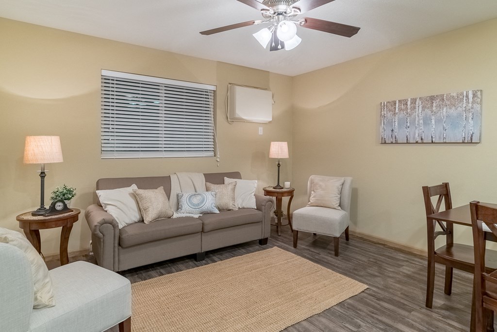 a living room with a couch and chairs and a ceiling fan