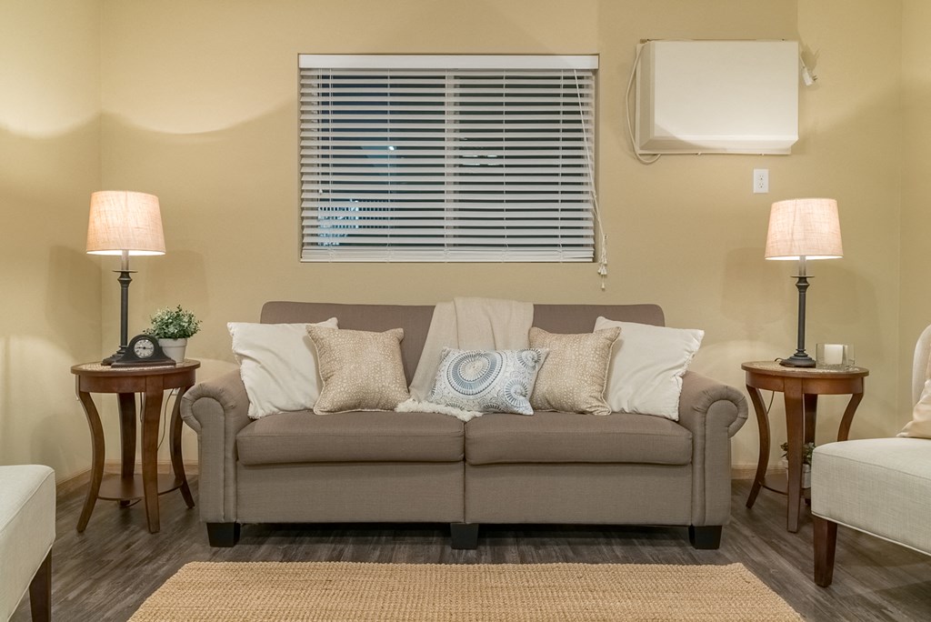 a living room with a couch and lamps and a window