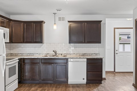 A kitchen with dark brown cabinets and a white fridge.