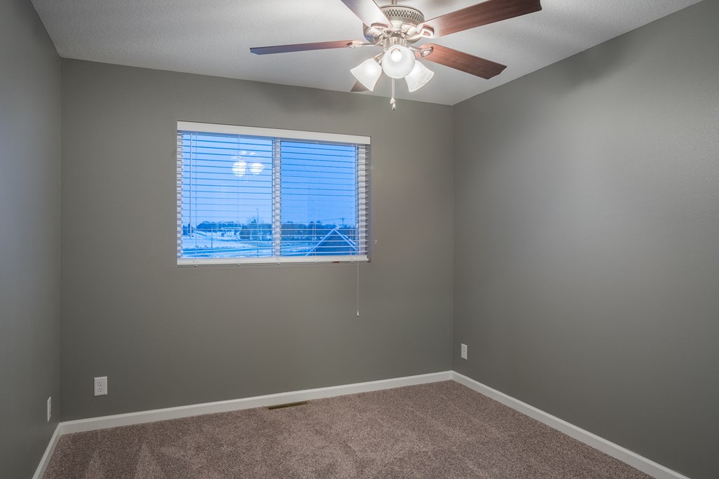 an empty bedroom with a large window and a ceiling fan