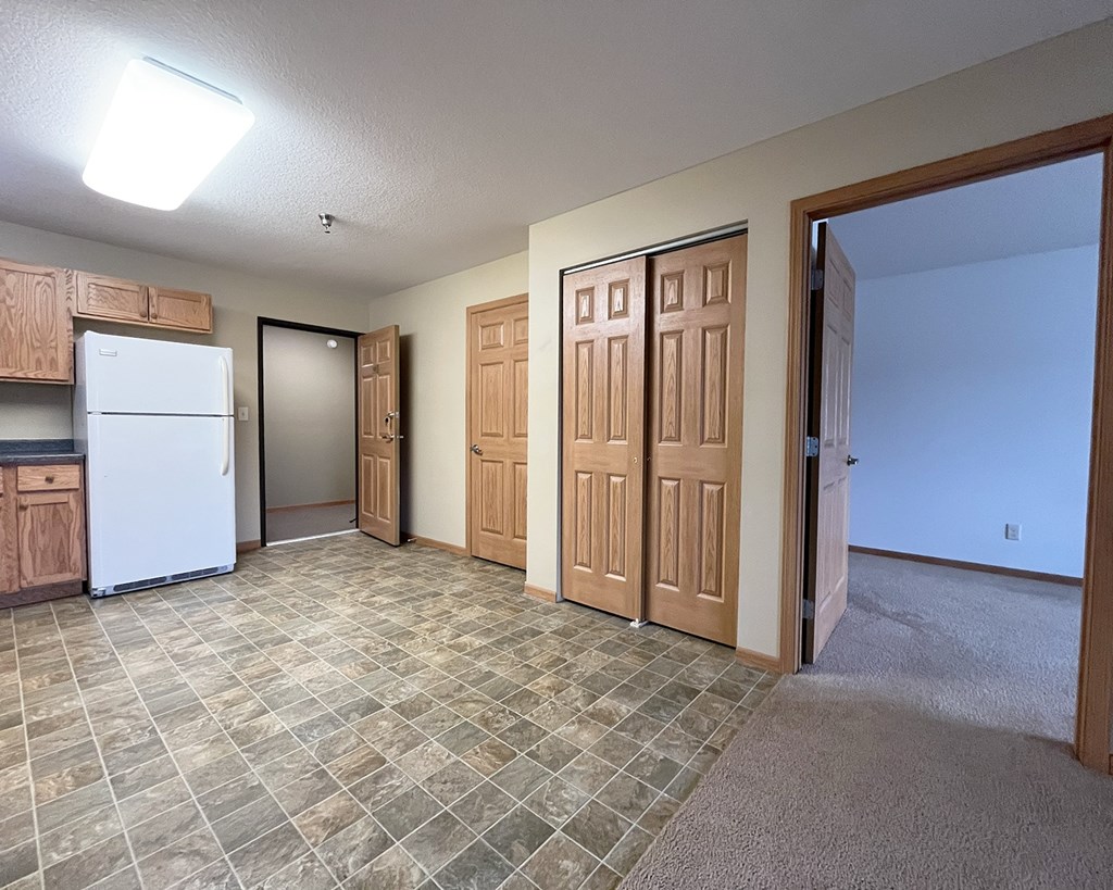 A kitchen with a white refrigerator and wooden cabinets.