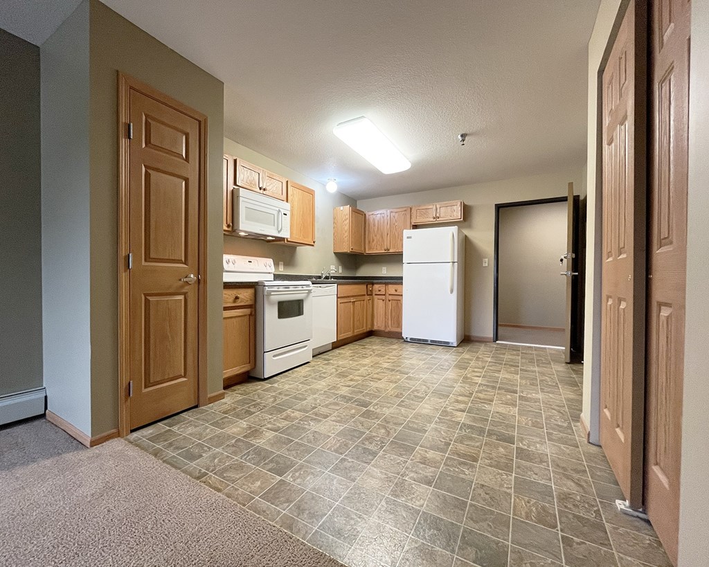 A kitchen with tile flooring and white appliances.