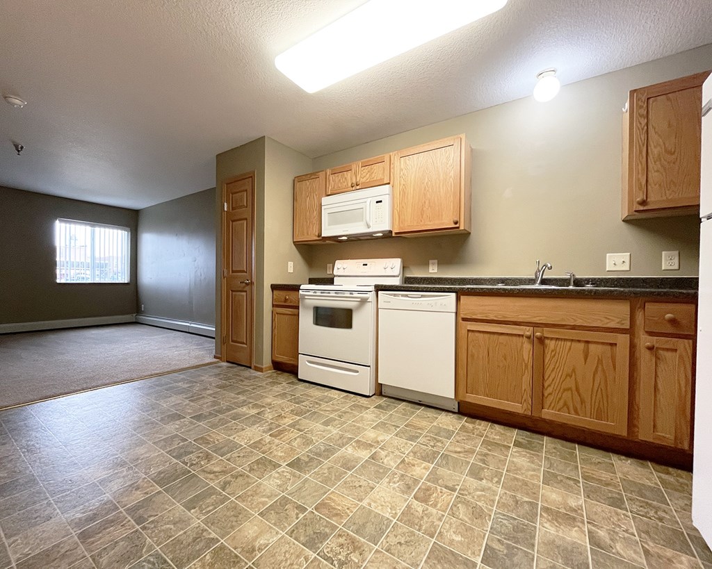 A kitchen with tile flooring and white appliances.