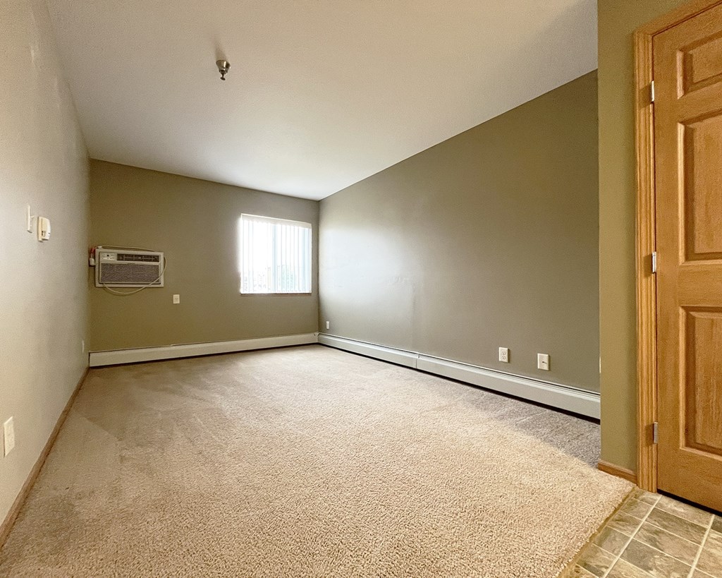 A room with a carpeted floor and a door on the right side.