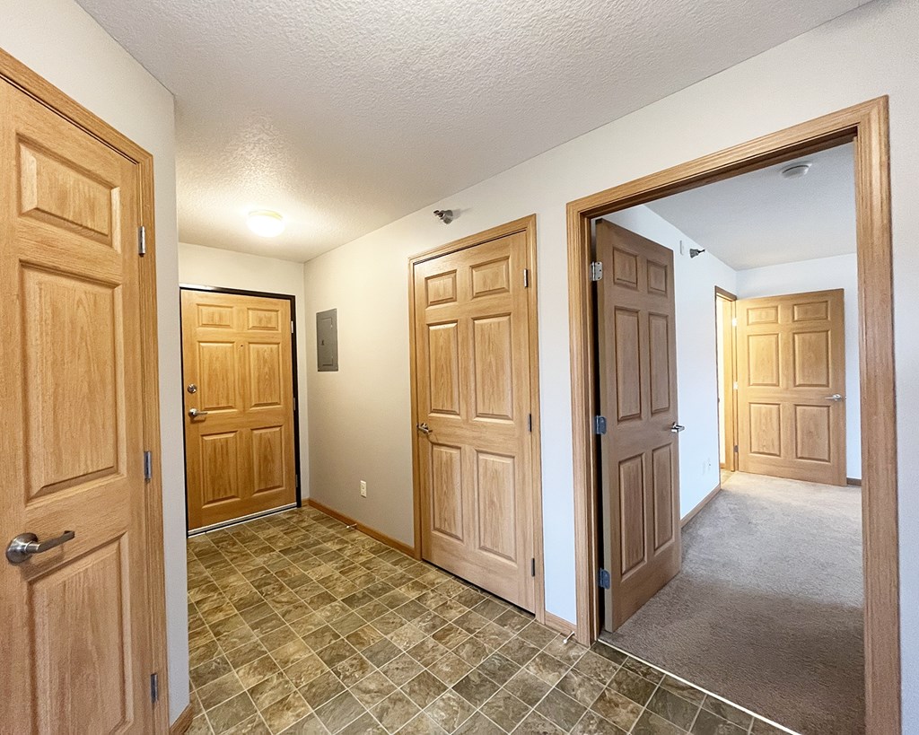 A hallway with four doors and a tiled floor.
