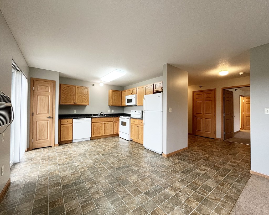 A kitchen with white appliances and wooden cabinets.