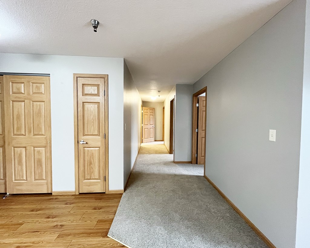 A hallway with two doors on the left and a carpet on the floor.