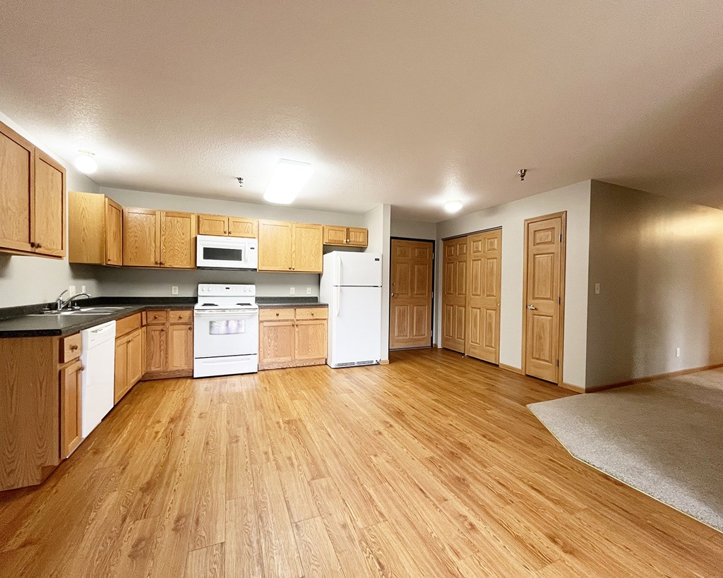 A kitchen with wooden floors and white appliances.