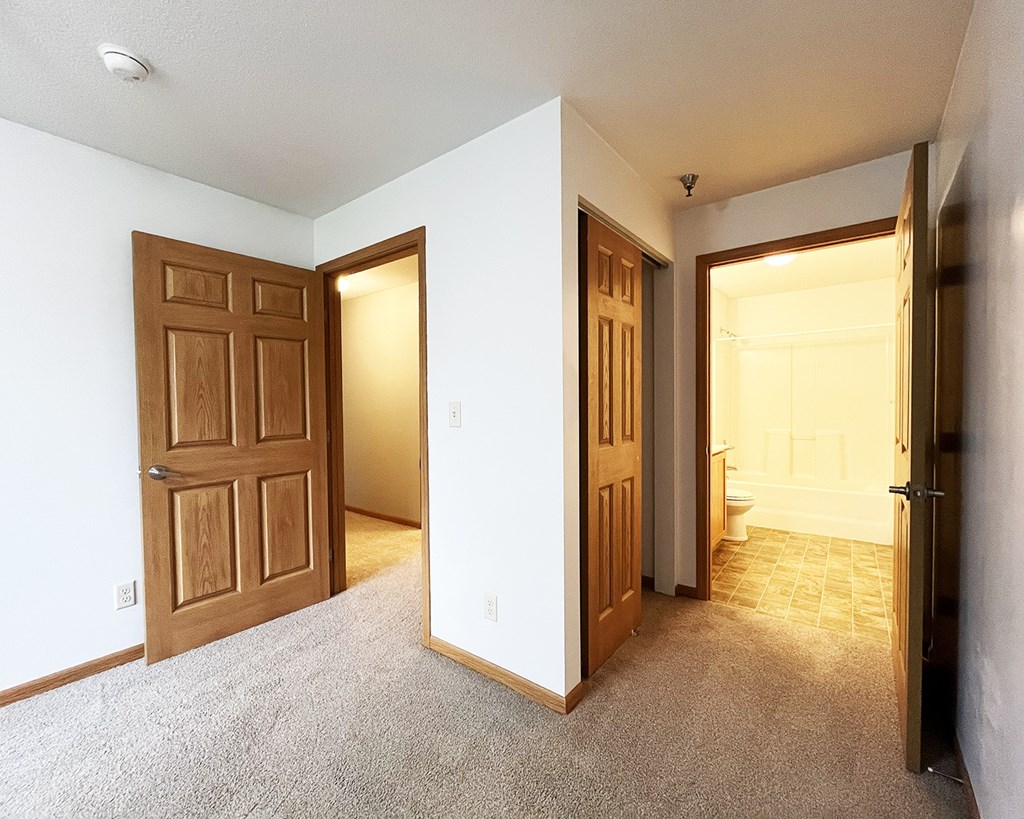 A room with a carpeted floor and three doors.