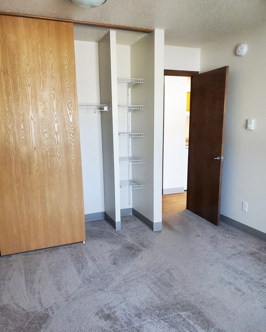 an empty room with a closet and a door to a bathroom