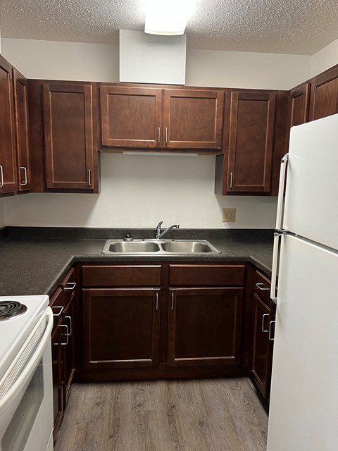 an empty kitchen with wooden cabinets and white appliances