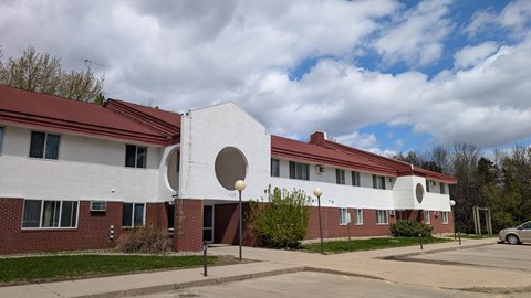A white building with a red roof and a large circular window on the side.