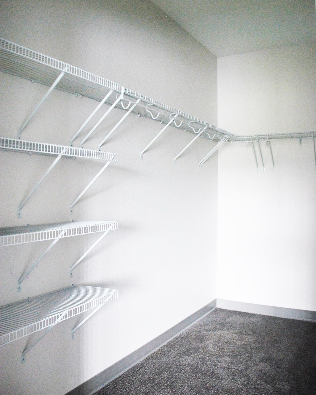 a walk in closet with white shelves and rails