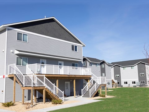 A grey and white apartment building with a balcony and stairs.