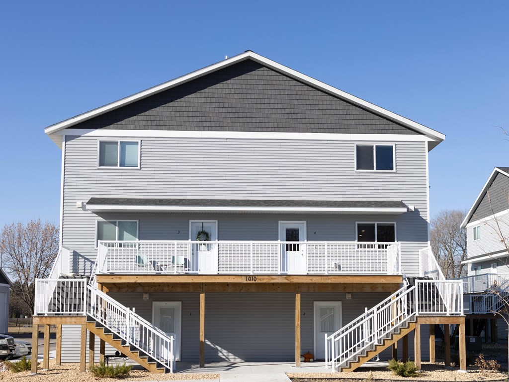 A two-story house with a balcony and stairs leading to the front door.