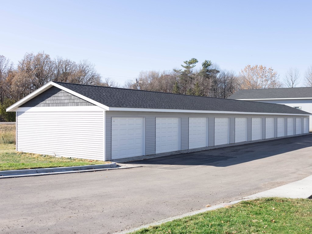 A long white garage with a black roof and a white car parked in front.