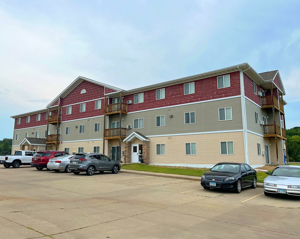 A parking lot in front of a multi-story apartment building.