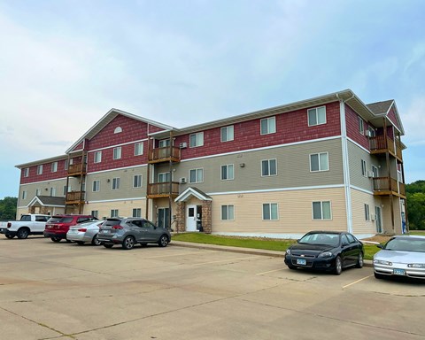 A parking lot in front of a multi-story apartment building.