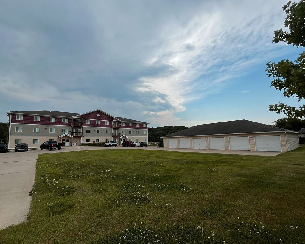 A large building with a red roof is surrounded by a grassy field.