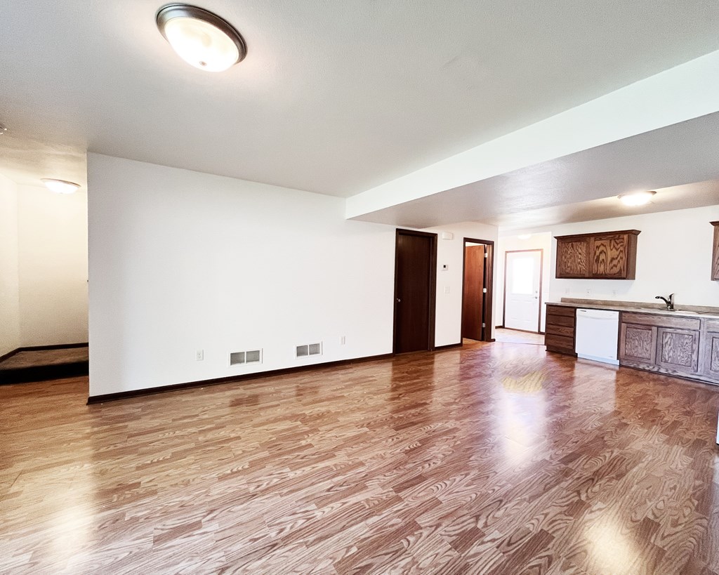 A room with wooden flooring and white walls.