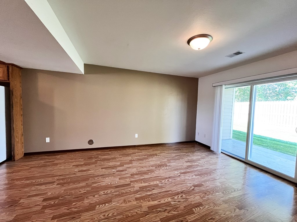A room with wooden flooring and a sliding glass door.