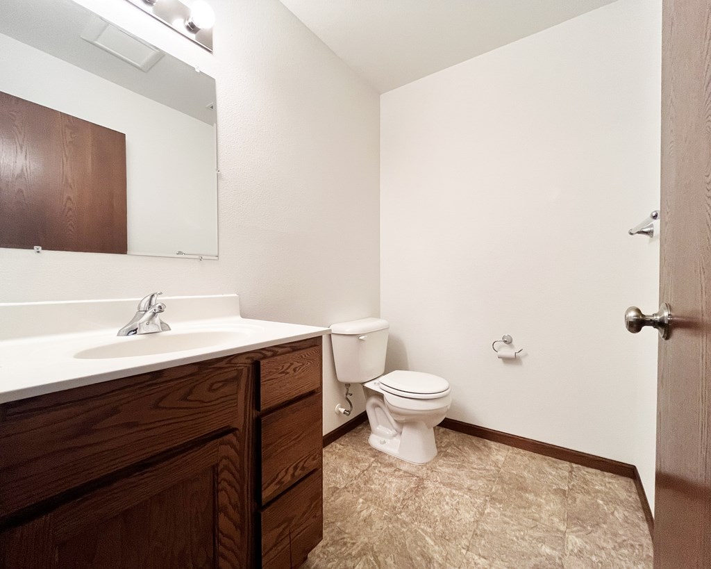 A white toilet sits in a bathroom next to a sink.
