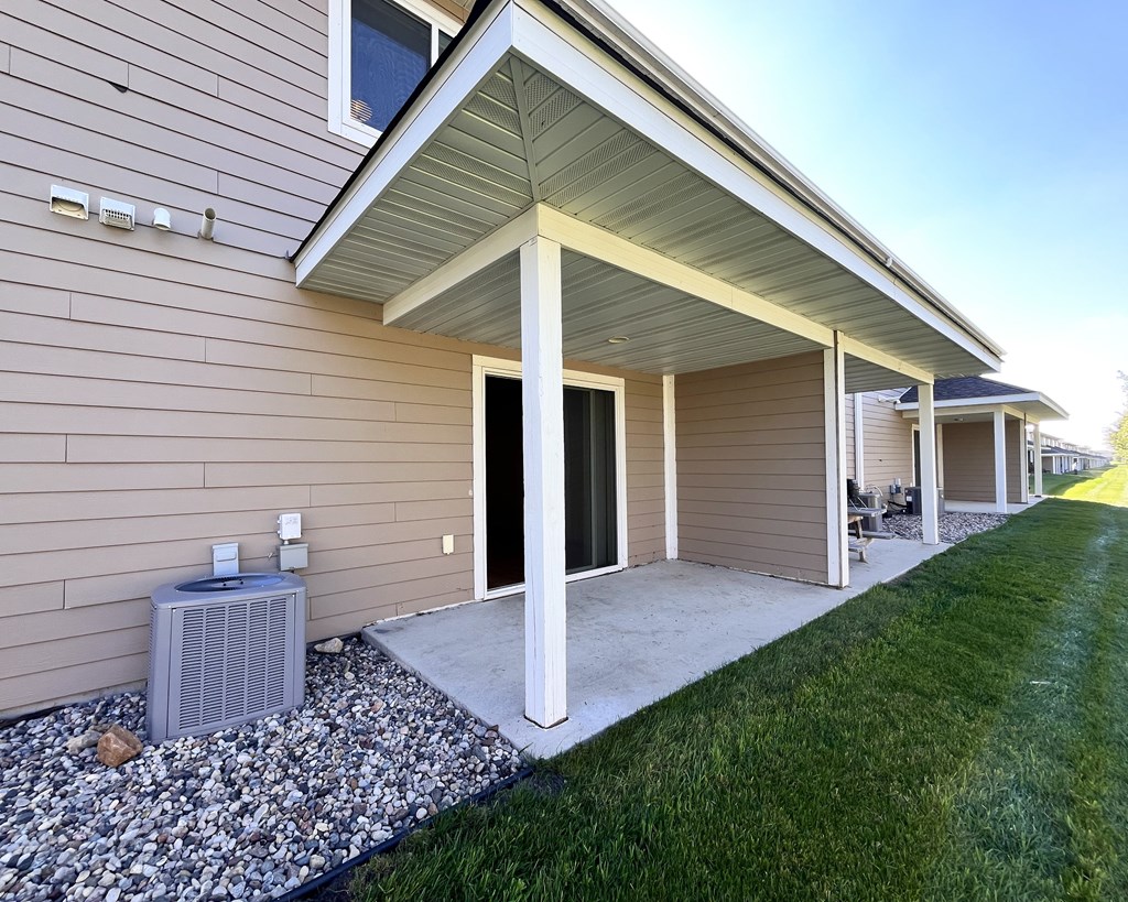 A house with a covered patio and a gray air conditioner.
