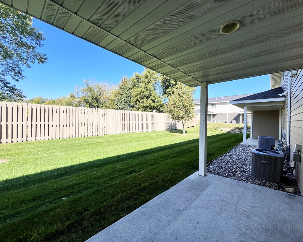 A backyard with a wooden fence and a covered patio area.