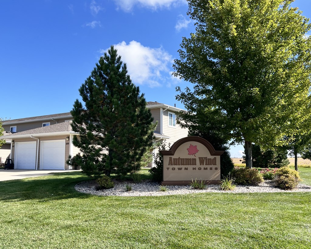 A sign for Autumn Wind Town Homes is in front of a house.
