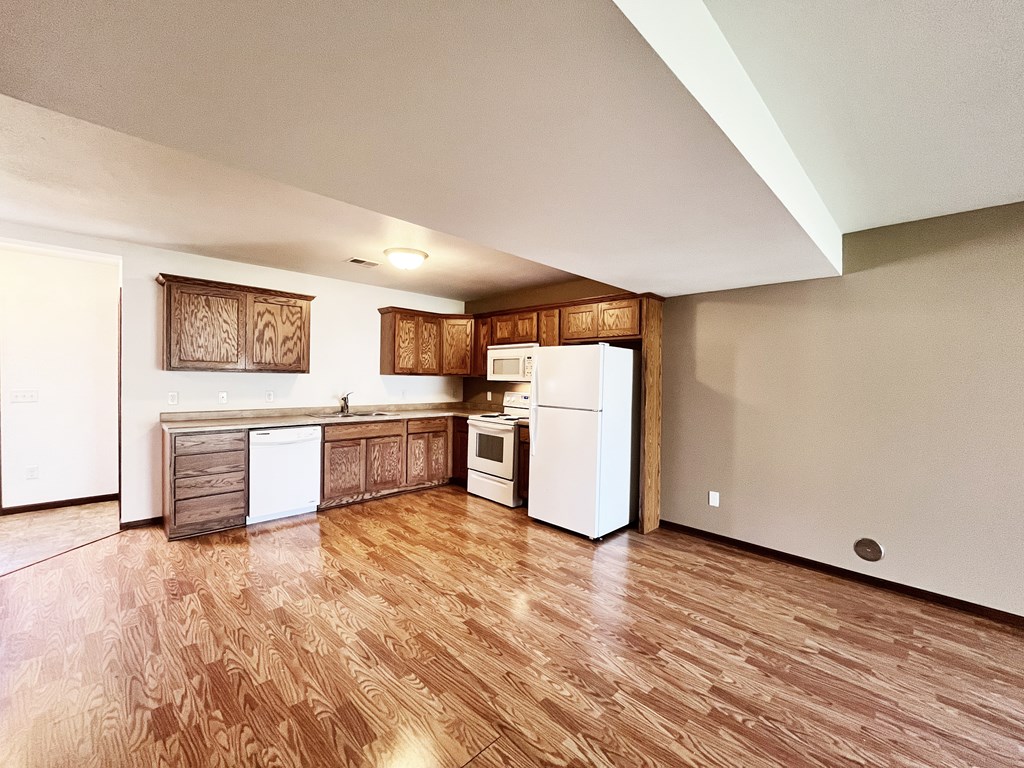 A kitchen with wooden floors and white appliances.