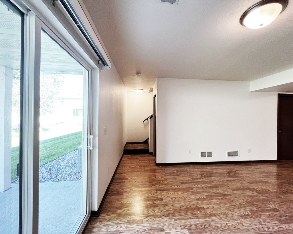 A room with a sliding glass door and a wooden floor.