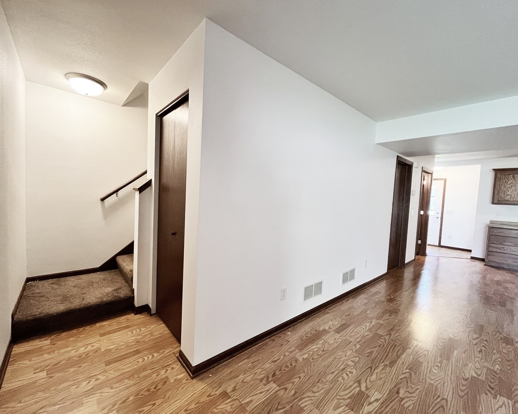 A hallway with a brown floor and white walls.
