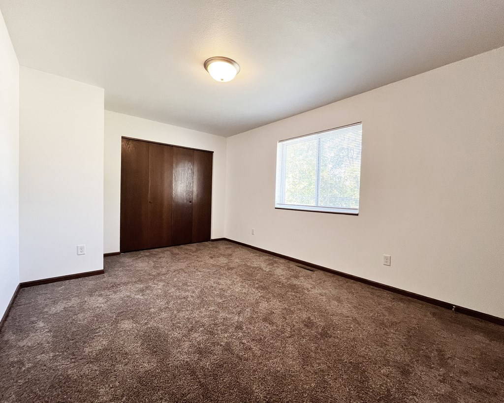 A room with a brown carpet and a brown door.