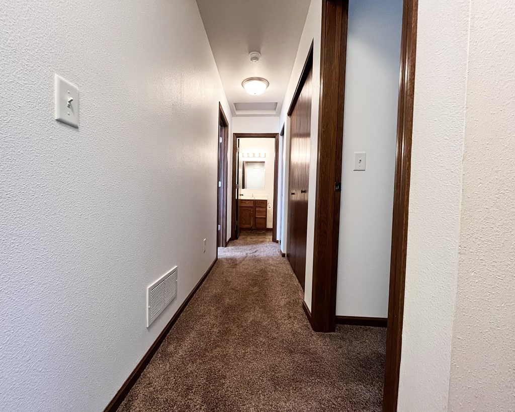 A long hallway with carpeted floors and white walls.