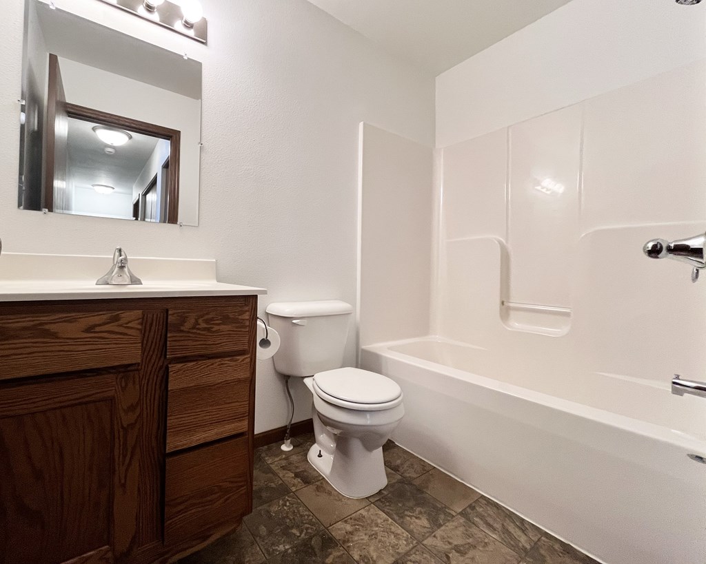 A white toilet sits next to a white bathtub in a bathroom.