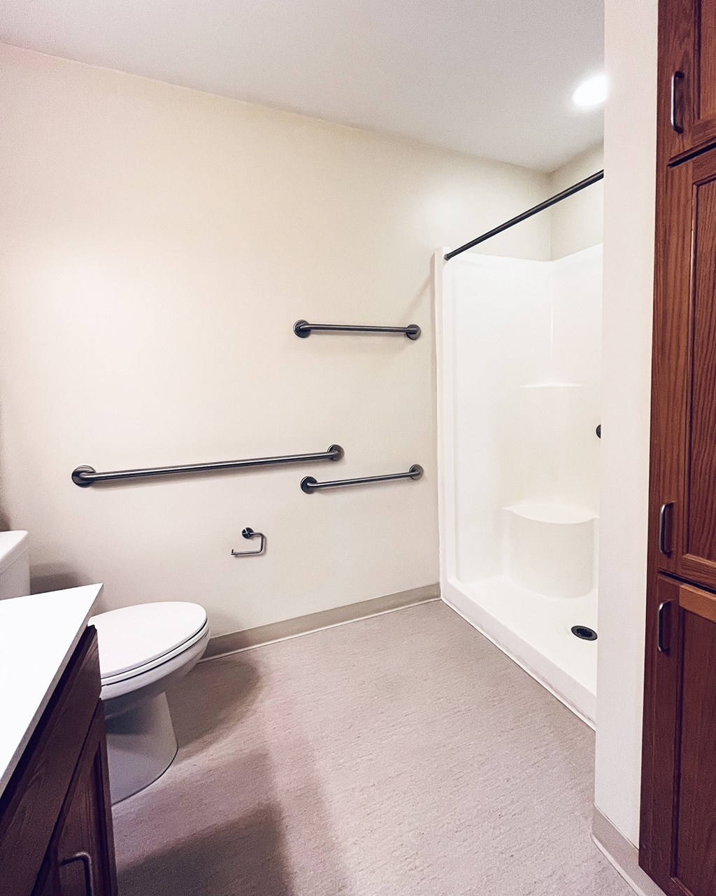 A bathroom with a toilet, a shower with a glass door, and a wooden cabinet.