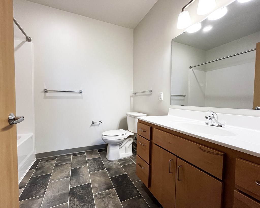 A bathroom with a toilet, sink, and a mirror.
