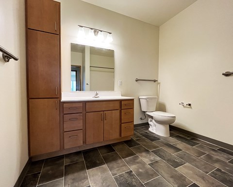 A bathroom with a toilet, sink, and wooden cabinets.