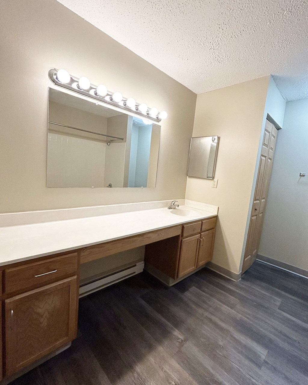 A bathroom with a vanity and a mirror with lights.
