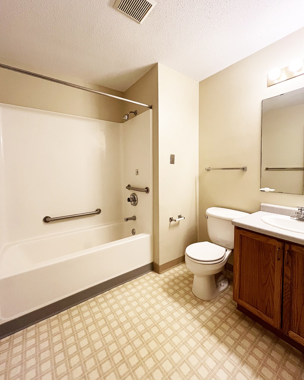 A white toilet sits in a bathroom next to a sink and bathtub.