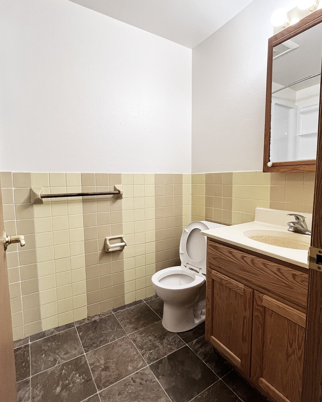 A bathroom with a toilet, sink, and tiled walls.