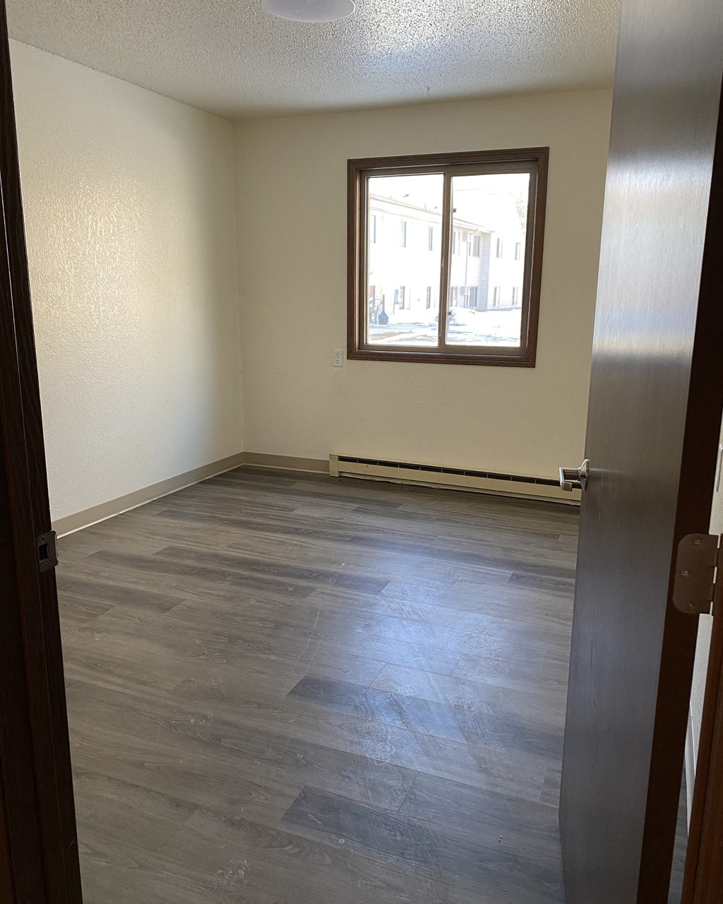 an empty room with wooden floors and a window