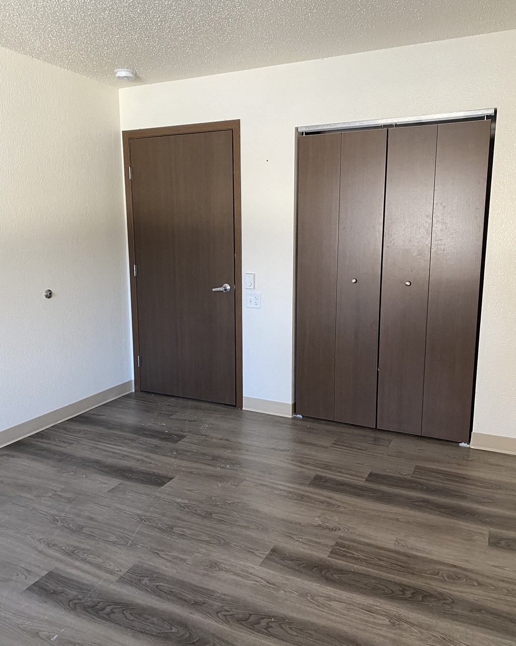 an empty living room with two doors and a wooden floor