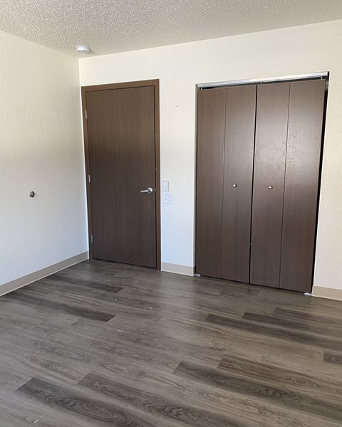 an empty living room with two doors and a wooden floor