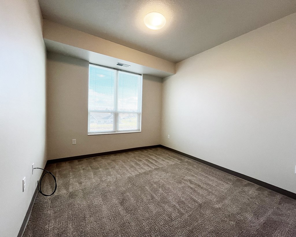 A room with a carpeted floor and a window.